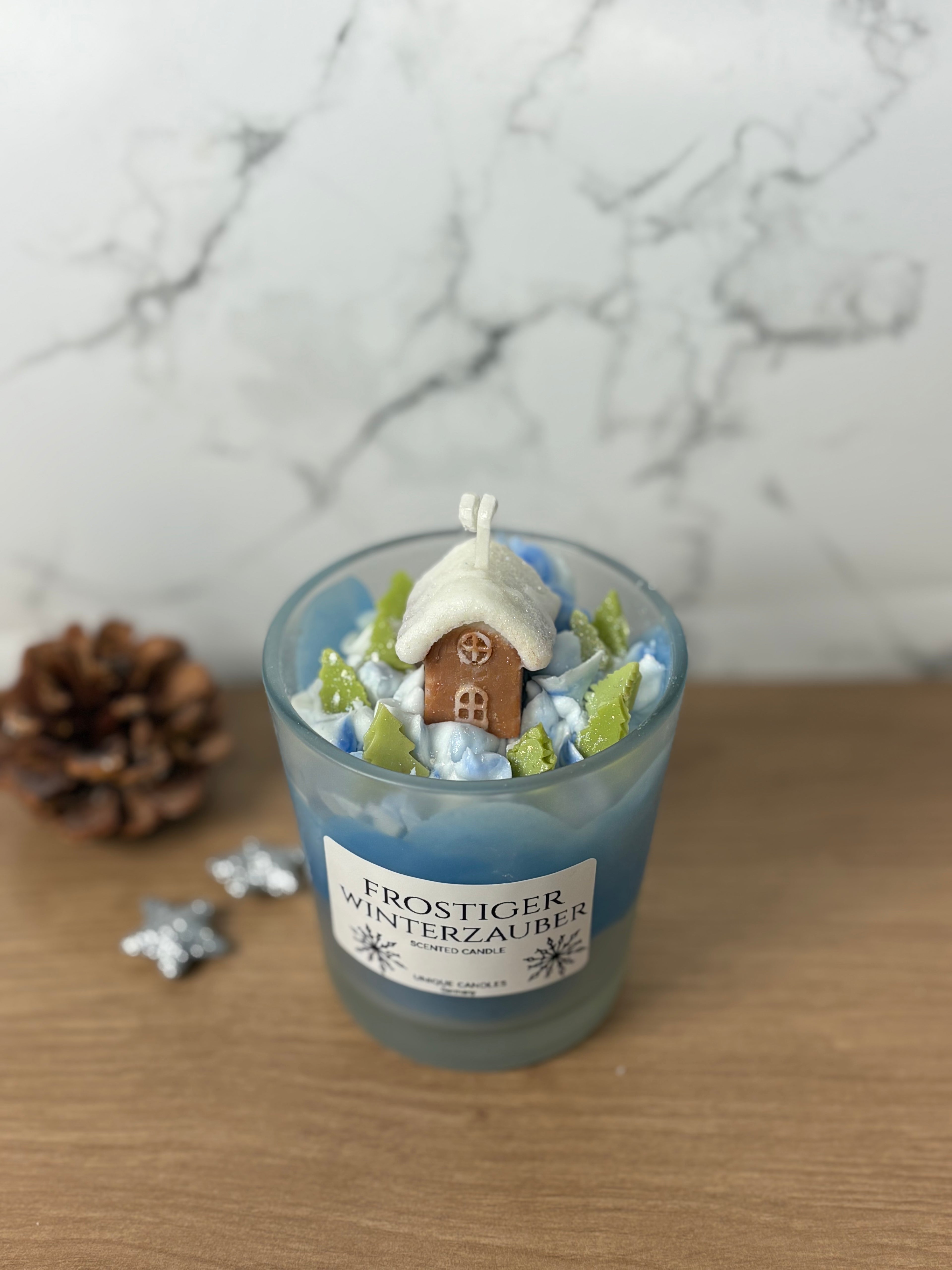 Handgemachte Behälterkerze "Frostiger Winterzauber" mit Häuschen- und Baum-Deko, ideal als duftende Winter-Tischdeko.