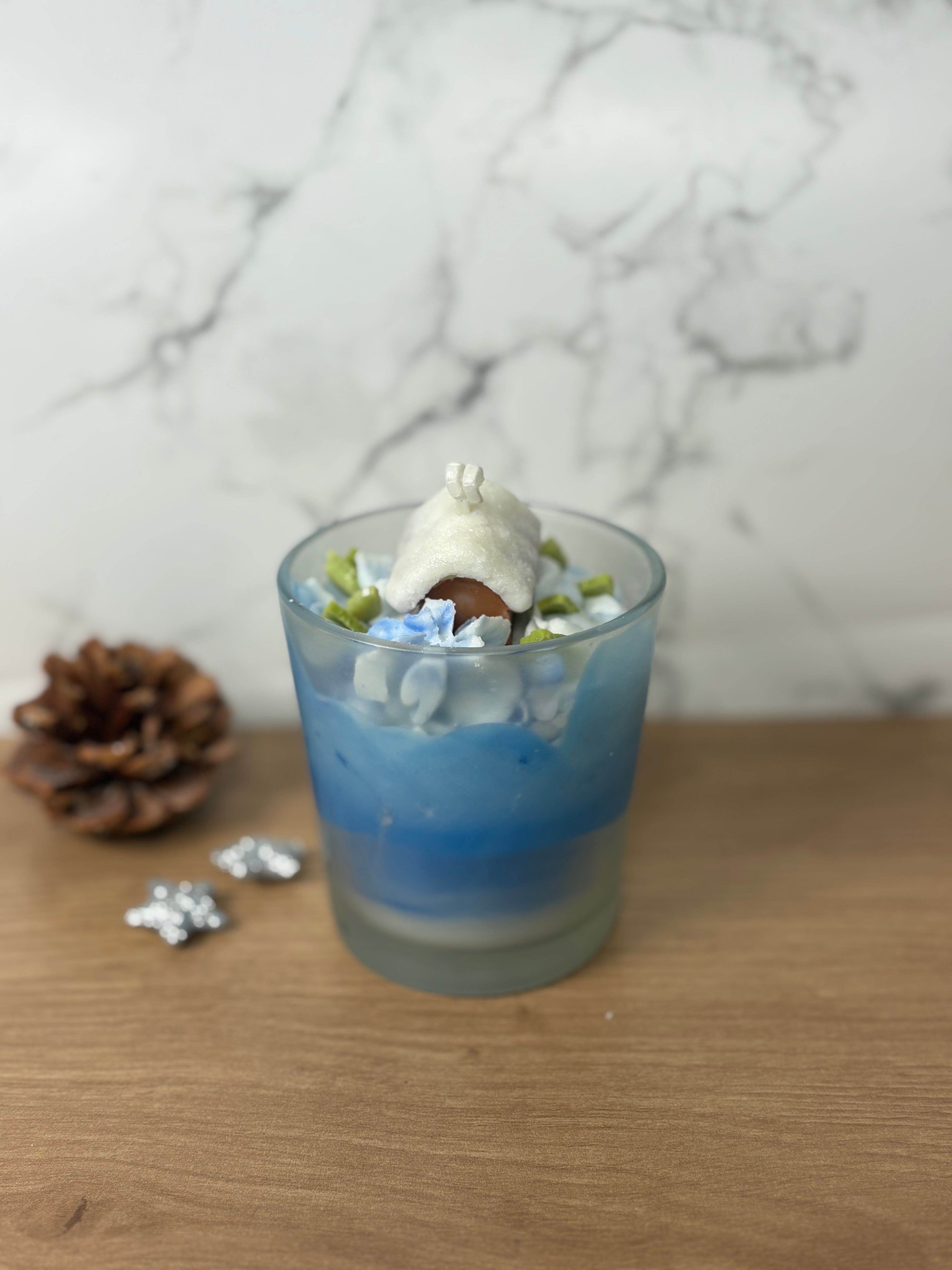 Handgemachte Behälterkerze "Frostiger Winterzauber" mit Häuschen- und Baum-Deko, ideal als duftende Winter-Tischdeko.