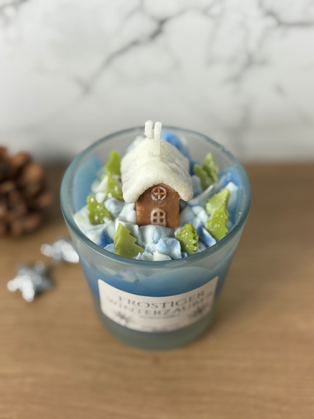 Handgemachte Behälterkerze "Frostiger Winterzauber" mit Häuschen- und Baum-Deko, ideal als duftende Winter-Tischdeko.