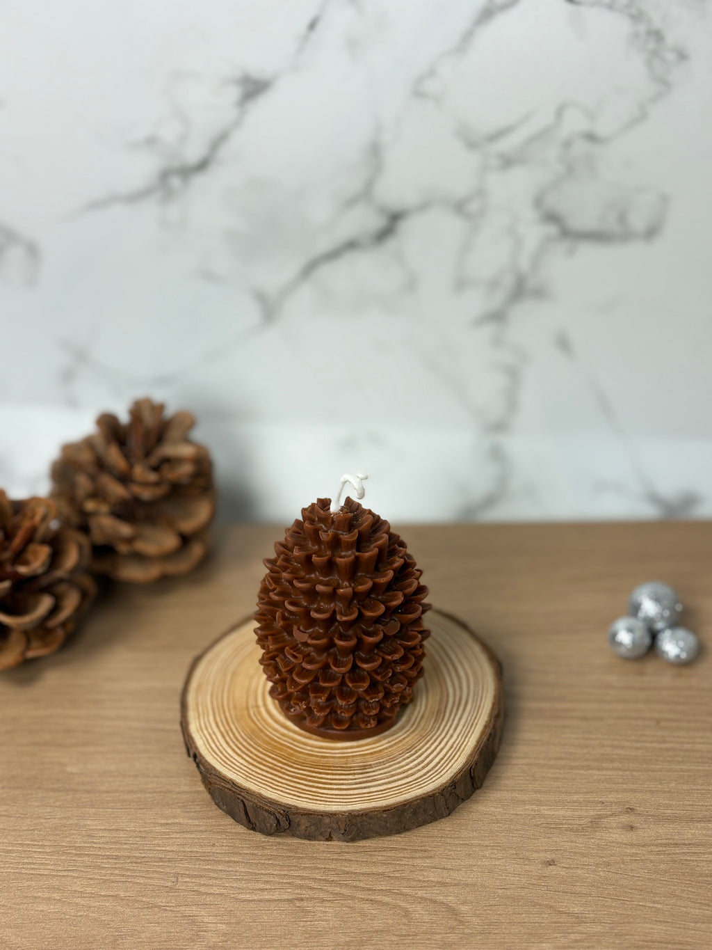 Handgemachte unbeduftete Tannenzapfen-Kerze aus 100% Bio-Sojawachs. Elegante, natürliche Deko in Form eines Tannenzapfens auf einem Holzuntergrund.